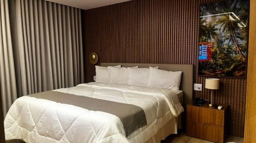 a bedroom with a large bed with white sheets at Hotel Amsterdam Montes Claros in Montes Claros