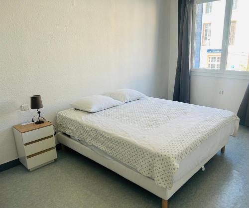 a bedroom with a bed with a nightstand and a window at Hôtel L'Acropole in Nissan-lez-Enserune
