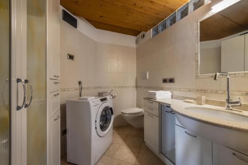 Un baño con lavadora y lavabo. en Villa Azzurra, Cloz Ospitar, en Cloz