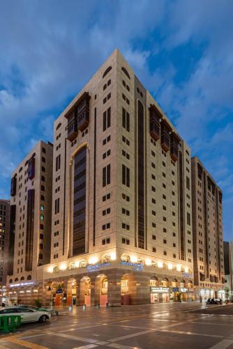 a large building with a car parked in front of it at Golden Tulip Al-Zahabi in Al Madinah