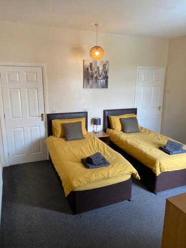 two beds in a room with yellow sheets and blue pillows at Albion House in Doncaster