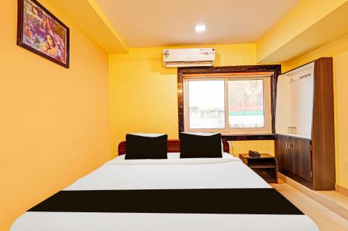 a bedroom with a large bed with yellow walls and a window at Super Collection O NAD Near Airport in Visakhapatnam