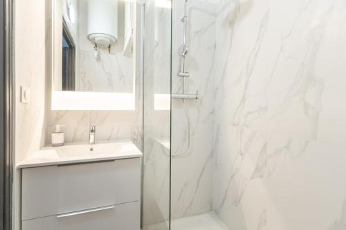 une salle de bain blanche avec une douche et un lavabo dans l'établissement Notre Dame & Mer, à Marseille
