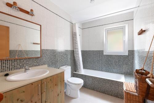 een badkamer met een wastafel, een toilet en een bad bij Villa Tres in Es Mercadal