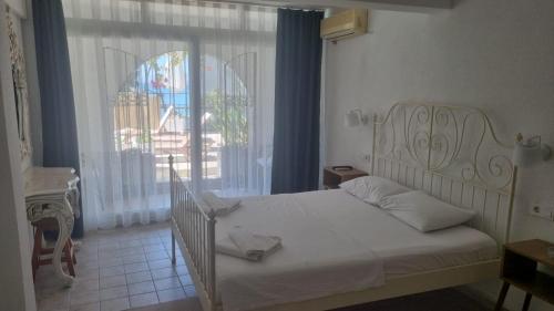 a bedroom with a white bed and a large window at Berg Pansiyon in Bodrum City