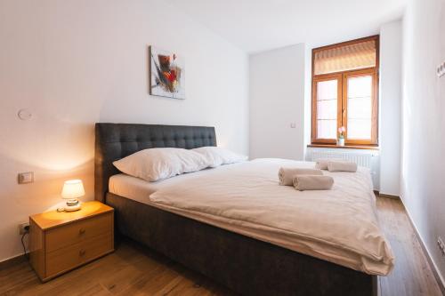 a bedroom with a bed with a nightstand and a window at Apartmány Elzet in Třeboň