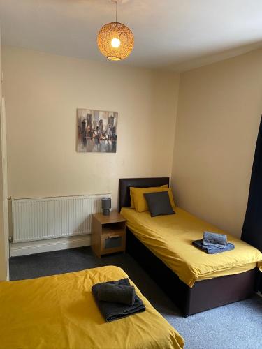 two beds in a room with yellow sheets at Albion House in Doncaster