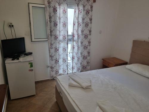 a bedroom with a bed and a television and a window at Berg Pansiyon in Bodrum City