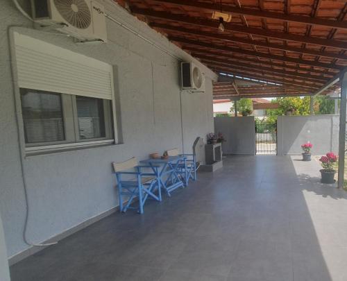 a patio with blue chairs and a table and a window at Villa Katerina in Polykárpion