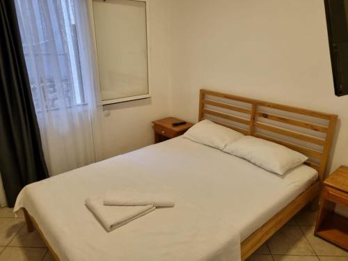 a bedroom with a white bed with a wooden headboard and a window at Berg Pansiyon in Bodrum City
