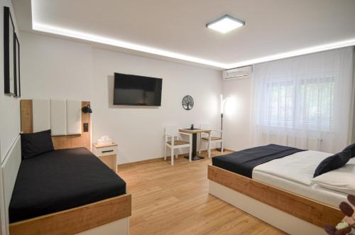 a bedroom with two beds and a tv on the wall at Residence Malva in Valtice