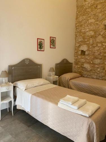 a bedroom with two beds and a stone wall at Corte Sicula in Syracuse