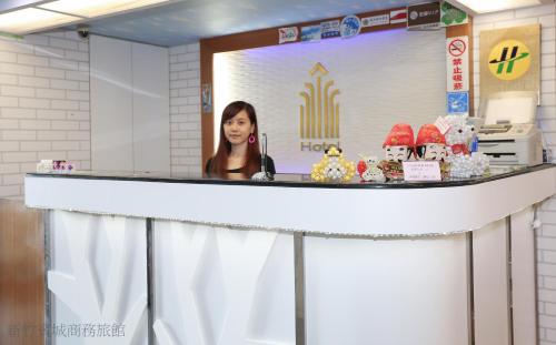 une femme parlant au téléphone derrière un comptoir dans l'établissement Bin Chen Business Hotel, à Hsinchu