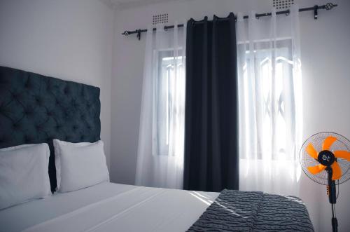 a bedroom with a bed with a fan and a window at Smooth apartments and tours in Livingstone