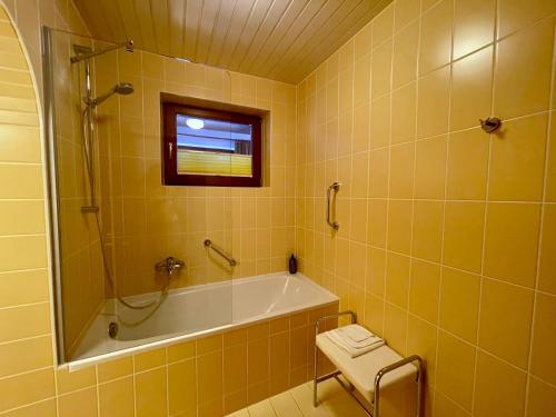 a yellow bathroom with a tub and a window at Hotel Garni Zerzer in Serfaus