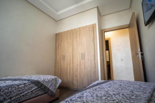 a bedroom with two beds and a wooden door at Charmante Deux Chambres et Salon Avec Jardin et Piscine à coté de plage in Casablanca