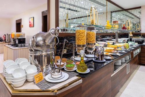a buffet line with dishes and drinks in a restaurant at Golden Tulip Al-Zahabi in Al Madinah