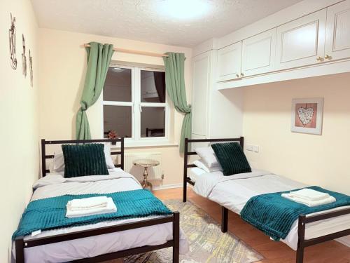 two beds in a bedroom with green curtains at Central Comfort Southampton, Free Parking in Southampton