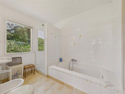 une salle de bain blanche avec une baignoire et un lavabo dans l'établissement Vue mer - Grande maison pour 7 adultes et 1 enfant, à Trévou-Tréguignec