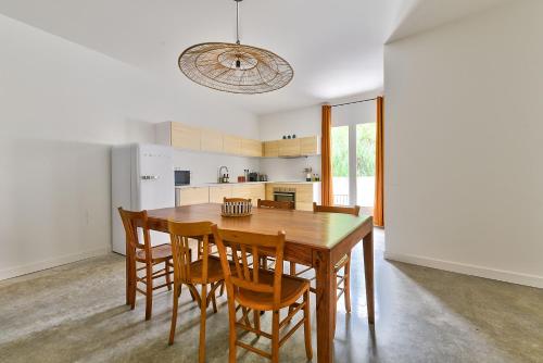 une cuisine et une salle à manger avec une table et des chaises en bois dans l'établissement NOCNOC Le Joïa - Petite piscine et jardin en ville, à Montpellier