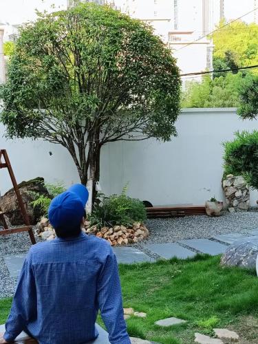 a person sitting on the ground looking at a tree at Eden Yard Boutique Hotel and Experiences in Xianghu