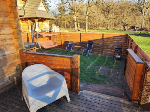a deck with chairs and a bench on a house at Woodorf drewnem usłane - domki z bala nad rzeką Słupią wśród pól i lasów z chatą grillową, ogniskiem i placami zabaw dla dzieci -Royal Red House z jacuzzi i ogrodzonym extra ogródkiem dla piesków, Royal Green House - bez jacuzzi in Ustka