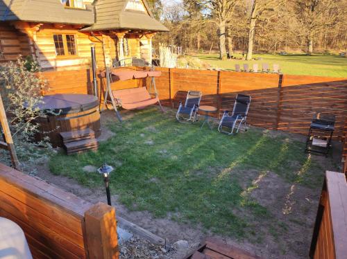 a backyard with chairs and a wooden fence at Woodorf drewnem usłane - domki z bala nad rzeką Słupią wśród pól i lasów z chatą grillową, ogniskiem i placami zabaw dla dzieci -Royal Red House z jacuzzi i ogrodzonym extra ogródkiem dla piesków, Royal Green House - bez jacuzzi in Ustka