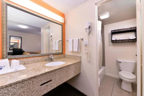 a bathroom with a sink and a toilet and a mirror at Americas Best Value Inn Ponca City in Ponca City