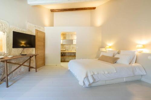 une chambre blanche avec un grand lit et un bureau dans l'établissement La Genive Arles Roquette, à Arles