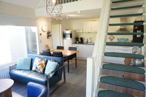 a living room and kitchen with a spiral staircase at Kustverhuur, Park Schoneveld, Duinroos 099 in Breskens