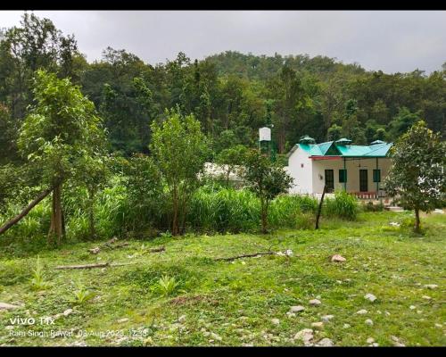 een huis met een groen dak in een veld bij Corbett hill center river home stay in Lansdowne