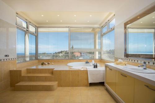a bathroom with a tub and two sinks and a large window at Luxury Villa Amaltheia Rhodes in Koskinou