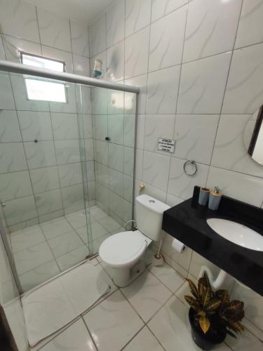 a bathroom with a shower and a toilet and a sink at Pousada Tiriri Guesthouse in Barra do Camaragibe