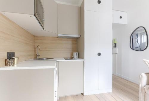 une cuisine avec des armoires blanches et un évier dans l'établissement Cozy Studio on Mobility Lease, à Boulogne-Billancourt