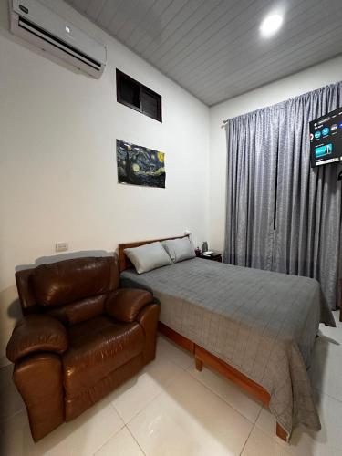 une chambre avec un lit et un canapé en cuir dans l'établissement Deluxe, à Catacamas
