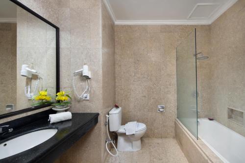 a bathroom with a toilet and a sink and a shower at Royal Hotel and Convention Tretes in Prigen