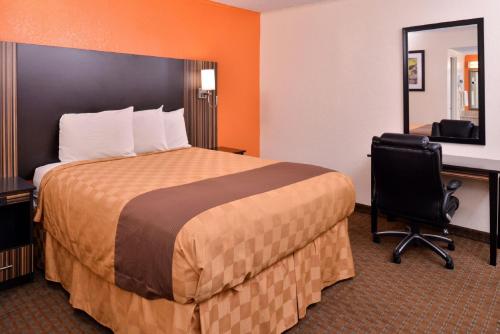 a hotel room with a bed and a desk and a mirror at Americas Best Value Inn Ponca City in Ponca City