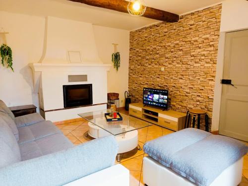 a living room with a couch and a tv at Entre montagne et lavande - Maison Provençale in Saint-Étienne-les-Orgues