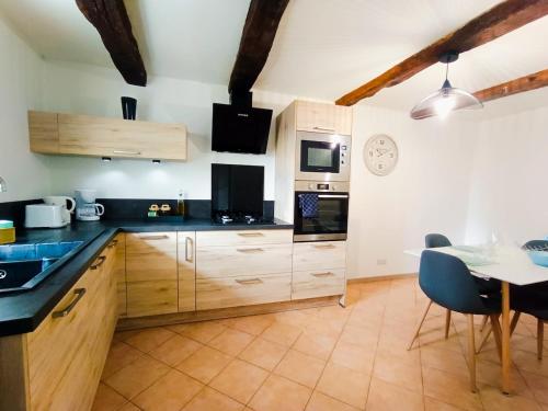 a kitchen with wooden cabinets and a table with chairs at Entre montagne et lavande - Maison Provençale in Saint-Étienne-les-Orgues