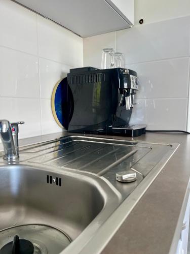 Un four micro-ondes est installé au-dessus d'un évier de cuisine. dans l'établissement La douceur Cannoise soit un 2P cosy terrasse piscine vue jardin proche plage à pied, à Cannes