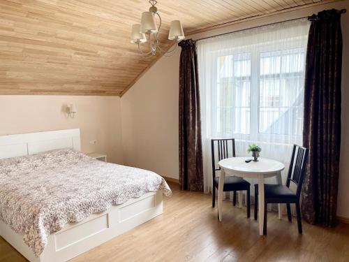 a bedroom with a bed and a table and a window at Svečių Apartamentai Vanagupėje in Palanga
