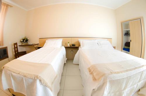 two beds in a hotel room with white sheets at Antico Plaza Hotel in Taubaté