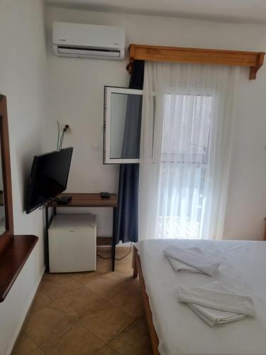a bedroom with a bed and a television and a window at Berg Pansiyon in Bodrum City
