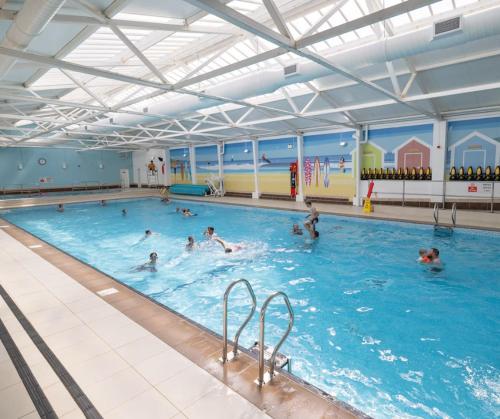 a group of people swimming in a swimming pool at Dune Breeze-Haven Perran Sands Holiday Park in Perranporth