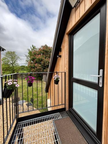 a sliding glass door on a house with flowers at The Cartlodge - Studio Loft Apartment in Horringer, Bury St Edmunds in Westley