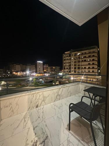 a table and a chair on a balcony at night at Bexhisteni lux rent in Shkodër