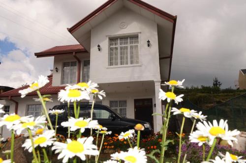 a black car parked in front of a house with flowers at Thuring's Holiday Bungalow in Nuwara Eliya