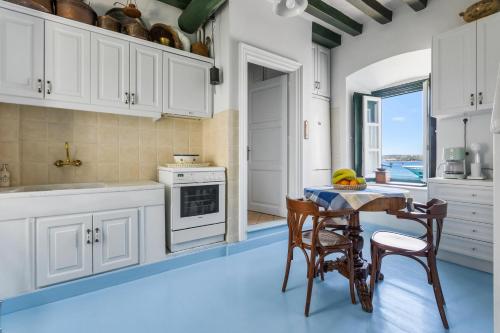 a kitchen with white cabinets and a table with chairs at 1800 MANSION in Spetses