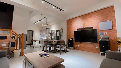 a living room with a television and a dining room at 宜蘭包棟民宿 蘭田會館 電動麻將 KTV Switch 德州撲克 燒烤 廚房 充電樁 寵物友善 in Yuanshan