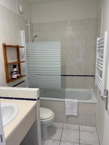 a bathroom with a tub and a toilet and a sink at Hôtel Michelet Plage in Soulac-sur-Mer